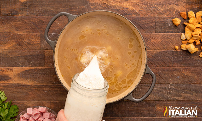 slowly pouring slurry into pot to thicken chicken cordon bleu soup