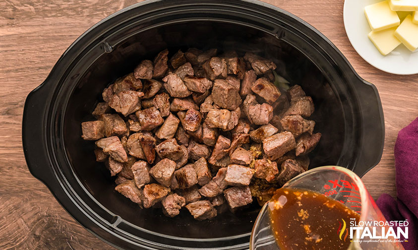 layering steak bites ingredients in a crockpot