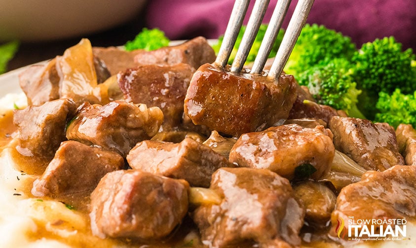 crockpot steak bites on a plate with mashed potatoes and gravy