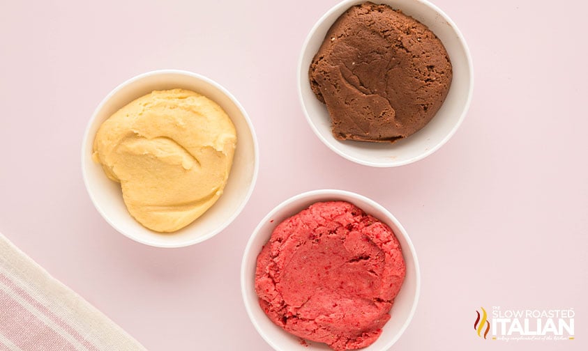 divided and colored neapolitan cookie dough in small bowls
