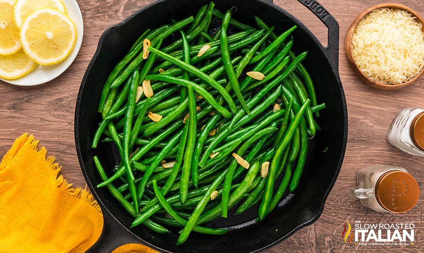 adding green beans to skillet with toasted garlic