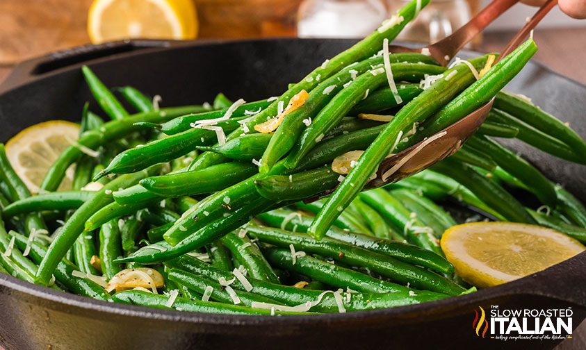 garlic green beans in a cast iron skillet with lemon slices