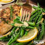closeup of garlic green beans whit chicken and a lemon wedge