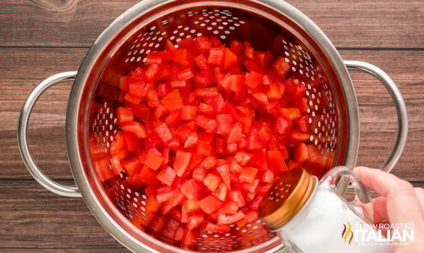 sprinkling diced tomatoes with salt in a colander