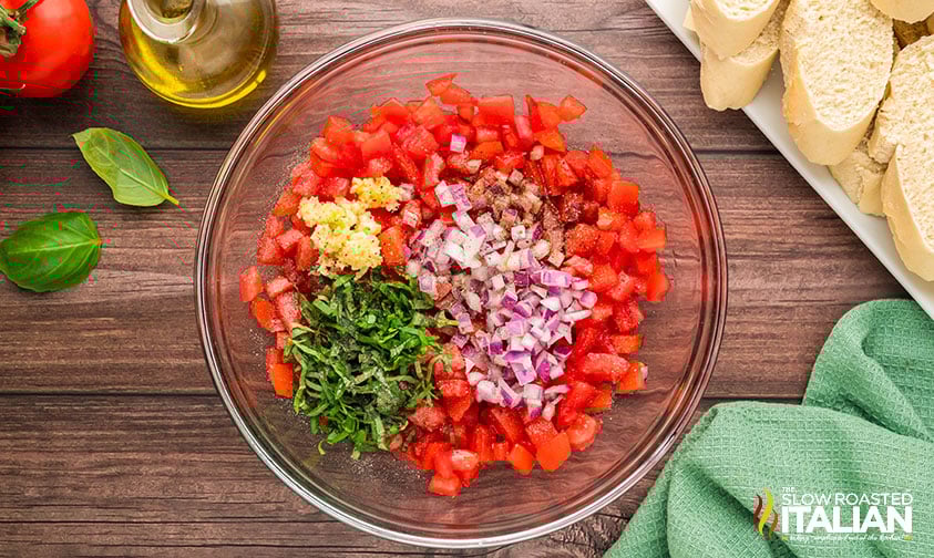 adding diced onion, basil, garlic and olive oil in a large bowl for easy bruschetta recipe