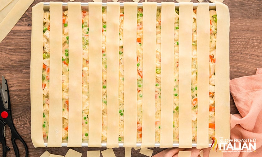 chicken pot pie mixture in a sheet pan with pie crust on top
