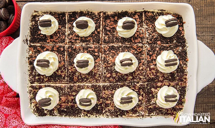 overhead: chocolate lasagna divided into 12 squares, each topped with whipped cream swirl and mini Oreo
