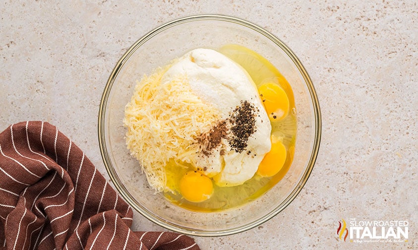 adding drained ricotta, eggs, grated parmesan and seasonings to large bowl