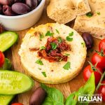 closeup of baked ricotta with sun dried tomatoes on a charcuterie board