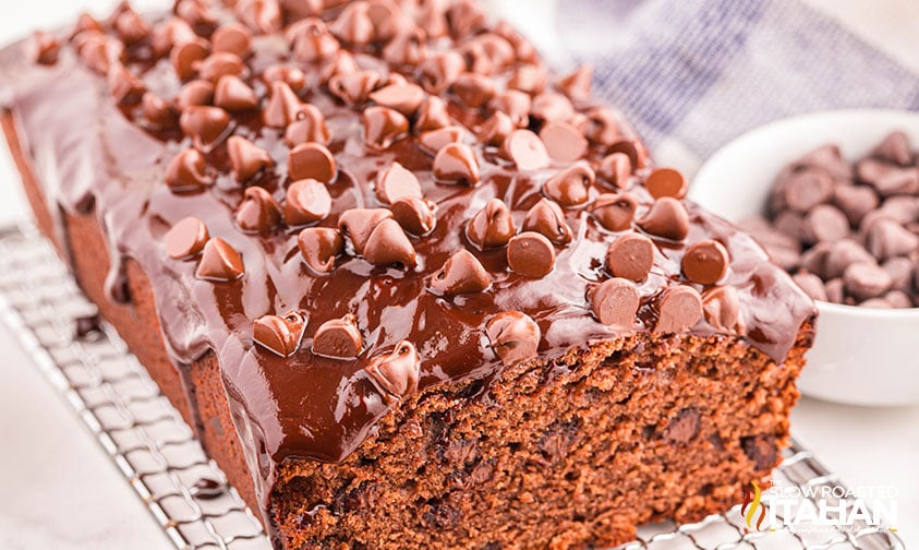 chocolate pound cake covered in chocolate topping and sprinkled with chocolate chips on a wire rack