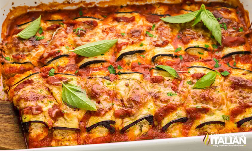 closeup of baked eggplant rollatini garnished with fresh basil