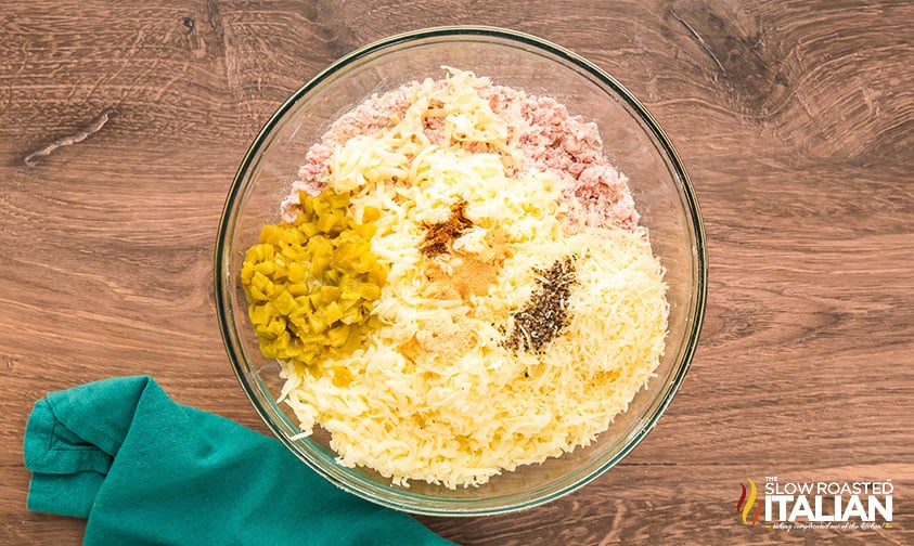 adding cheeses, seasonings and milk yo sausage and biscuit mix in a large bowl