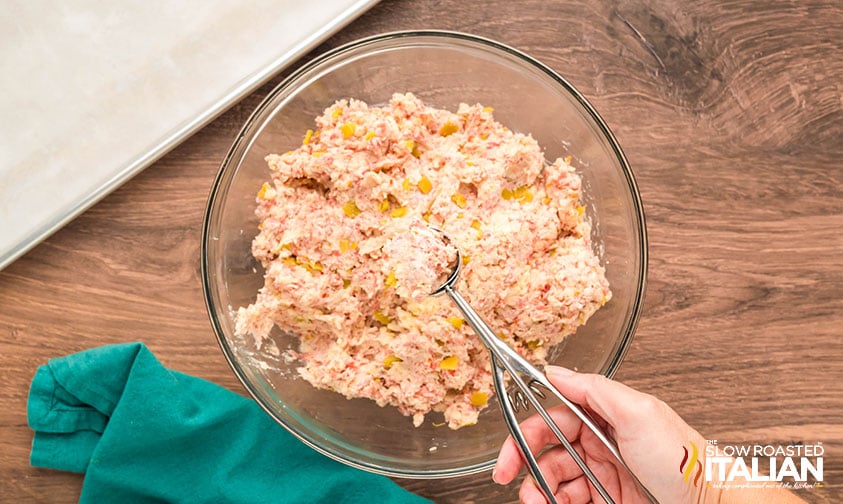 scooping out sausage popper dough in a cookie scoop for easy rolling