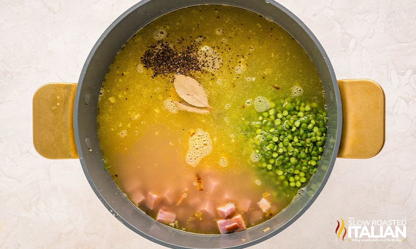 adding chicken stock, ham, and split peas to pot