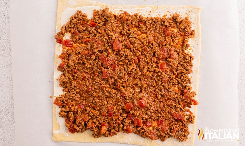 taco pinwheels mixture spread out onto a sheet of puff pastry