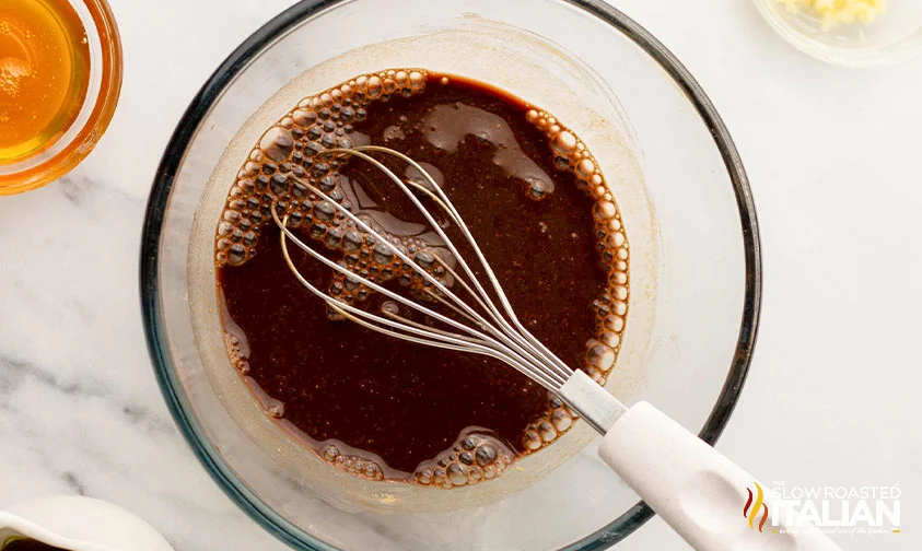 whisking balsamic salad dressing in clear bowl