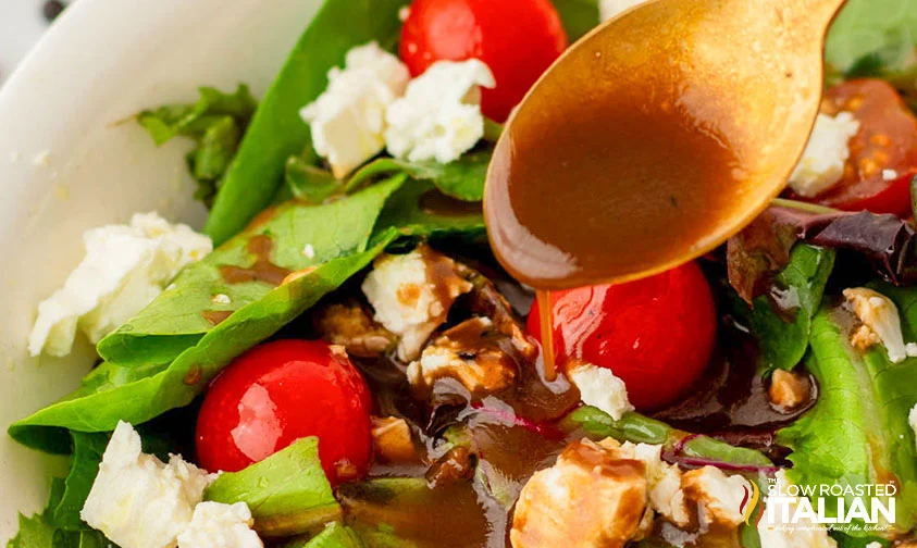 spooning balsamic vinaigrette dressing over salad