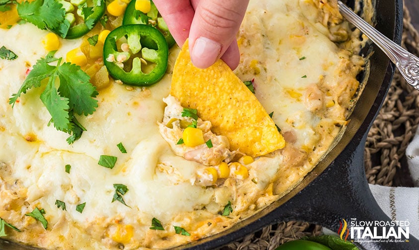 scooping chicken enchilada dip with a tortilla chip