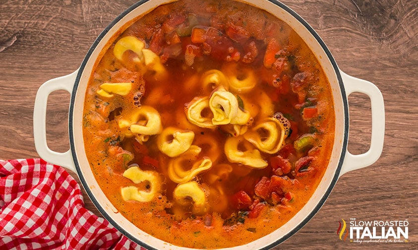 cheese tortellini added to soup in a large pot