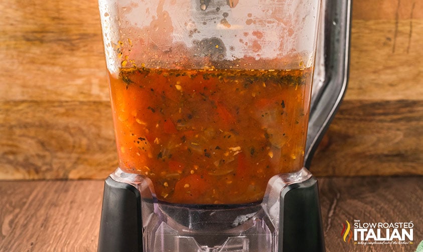adding roasted tomato soup ingredients to a blender