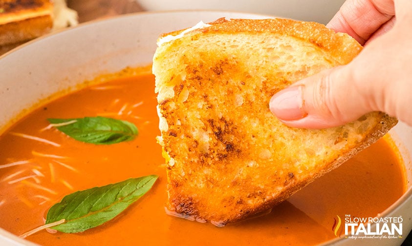 dipping grilled cheese into roasted tomato soup