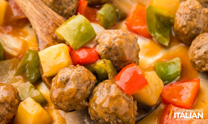 closeup of sweet and sour meatballs on a wooden spoon