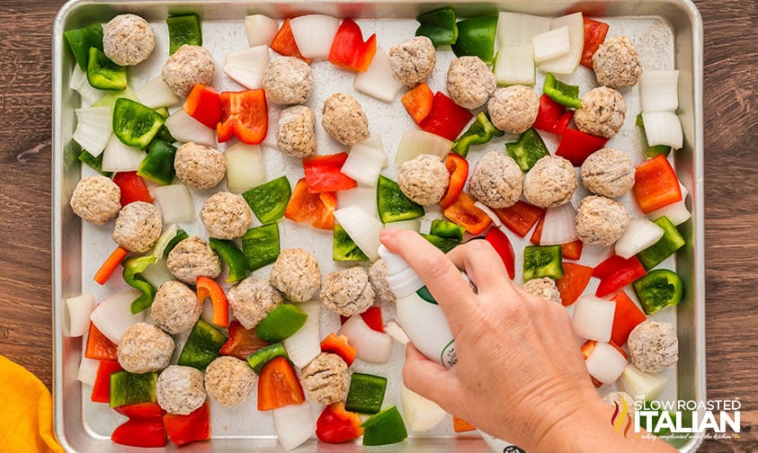 spraying meatballs, onions and peppers with olive oil