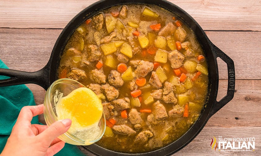 adding melted butter and flour to pork stew in cast iron skillet