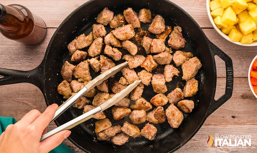 browned pork stew meat in a cast iron skillet