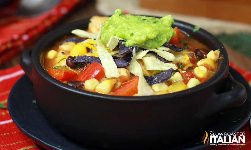 closeup of chicken tortilla soup in a bowl topped with tortilla strips and guacamole