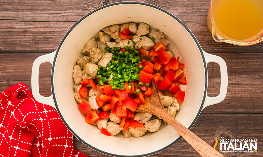 adding green and red peppers to chicken tortilla soup base