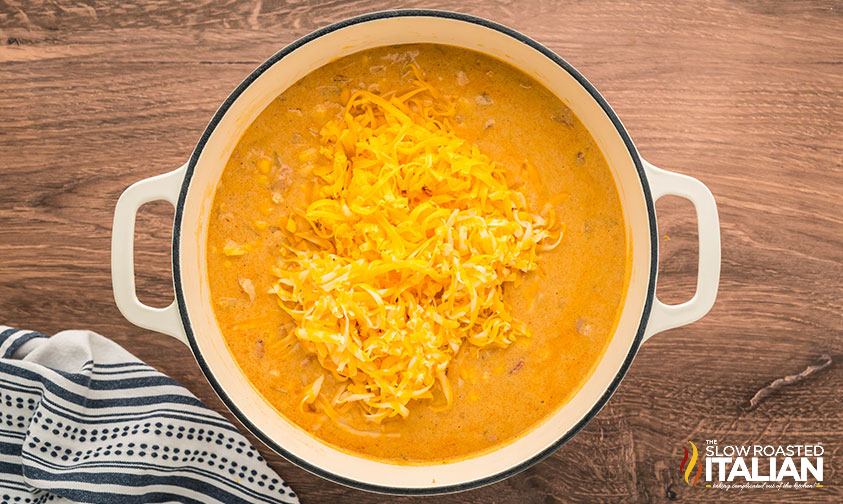 adding shredded cheese to chicken bacon corn chowder