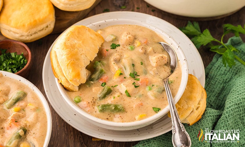 chicken pot pie soup in a bowl with half of a biscuit