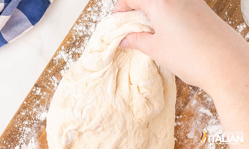 kneading soft pretzel dough on a floured wooden board