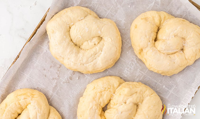 shaped soft pretzels on a parchment lined baking sheet