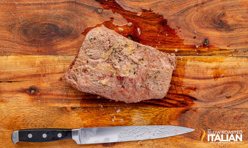 cooked corned beef on a wooden board with a sharp knife