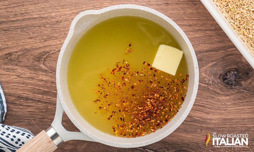 heating chicken stock, butter, and seasoning in a small pot for spicy rice