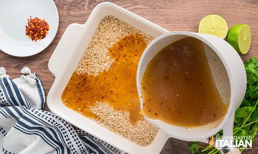 pouring hot liquid over spicy rice n a baking dish