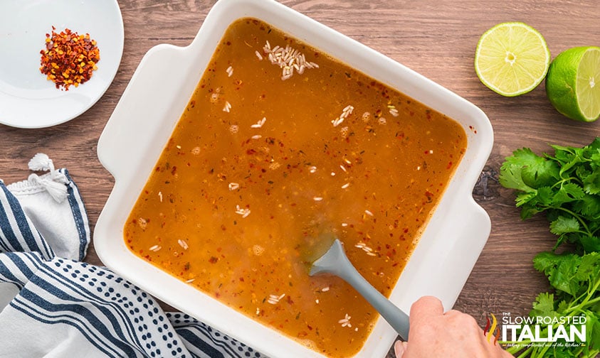 mixing uncooked spicy rice with hot liquid in a baking dish