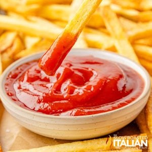 closeup of beef tallow french fries dipped in a small bowl of ketchup