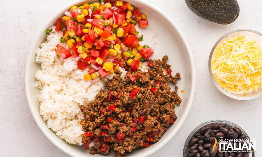 adding salsa to ground beef and rice for a taco bowl