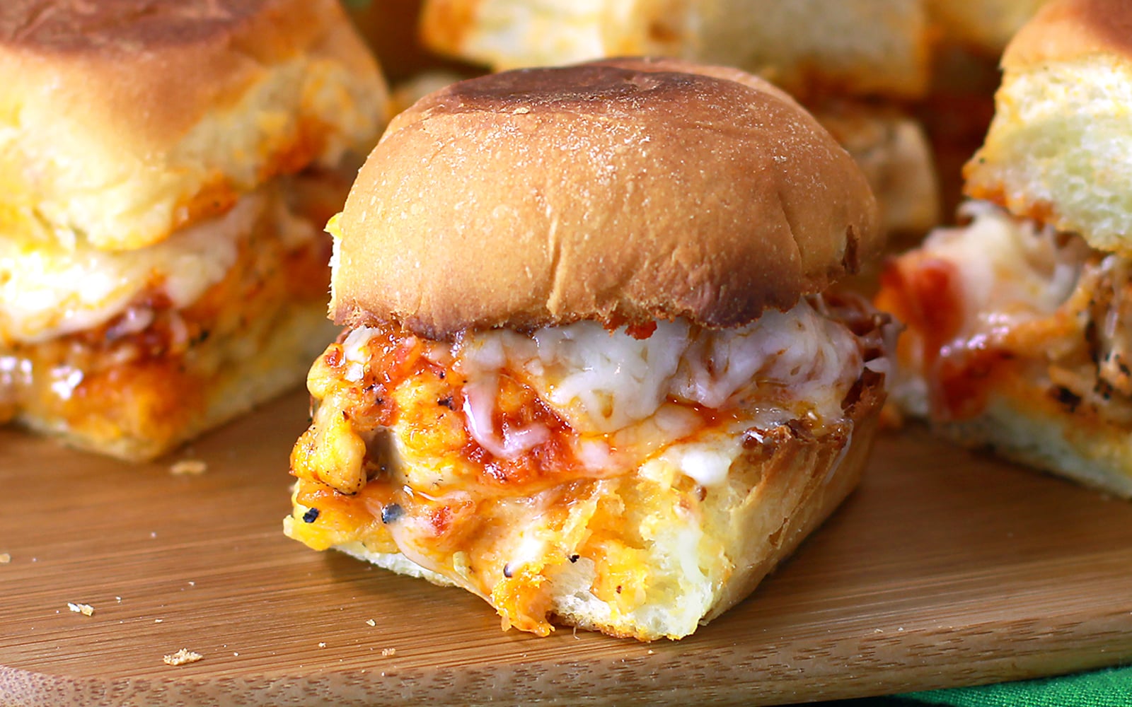 closeup of chicken parmesan sliders on a wooden board