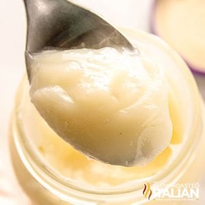 closeup of beef tallow on a spoon over a glass jar