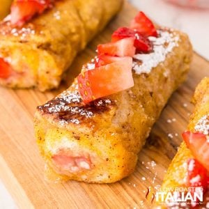 closeup of french toast roll ups with diced strawberries and powdered sugar on top