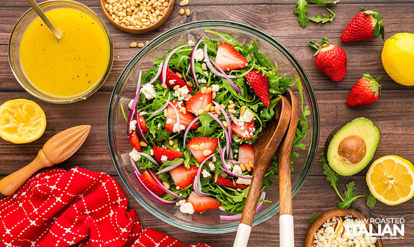 ingredients for arugula salad recipe in a large glass bowl