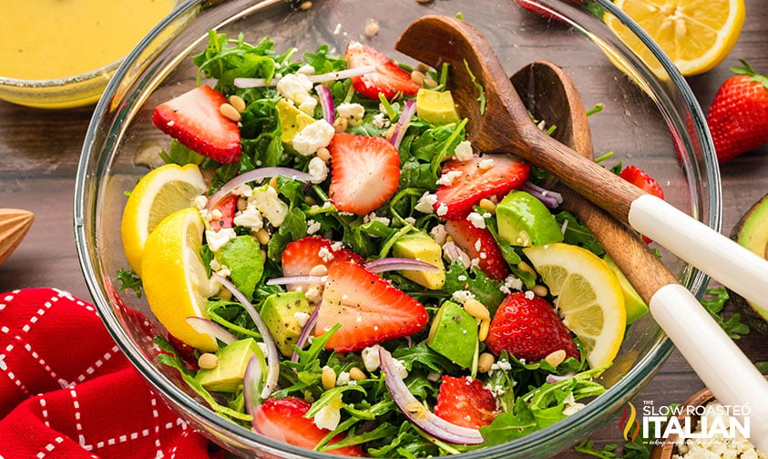 arugula salad recipe in a lard bowl with wooden spoons