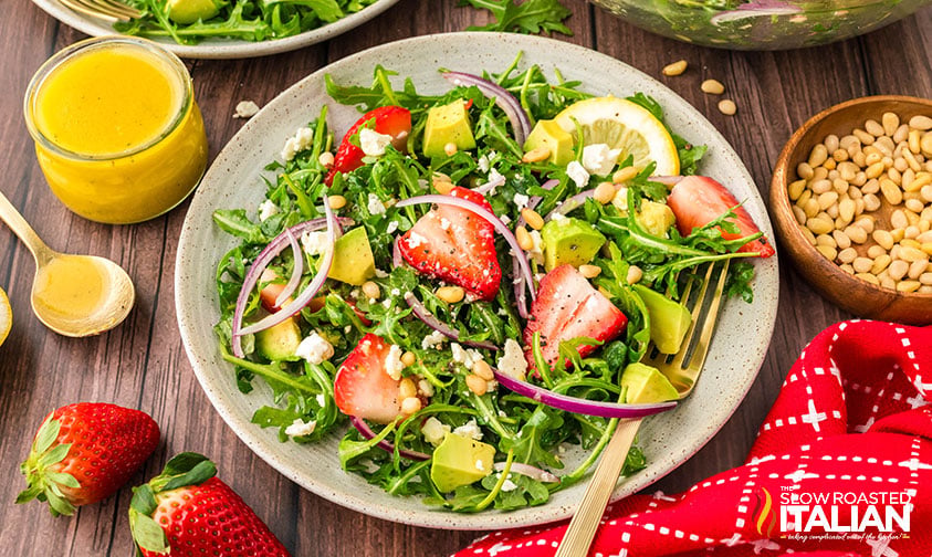 plate of arugula salad recipe with a jar of homemade dressing