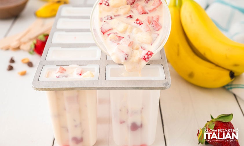pouring banana split popsicles mixture into popsicle molds