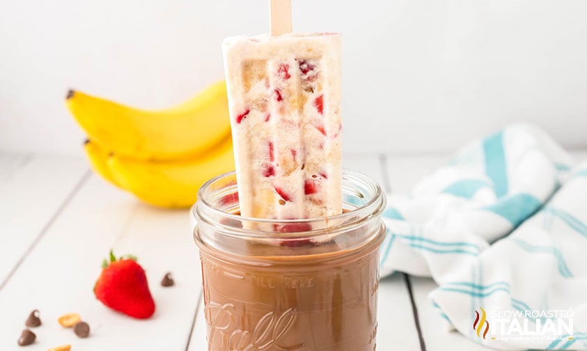 dipping banana split popsicles in melted chocolate