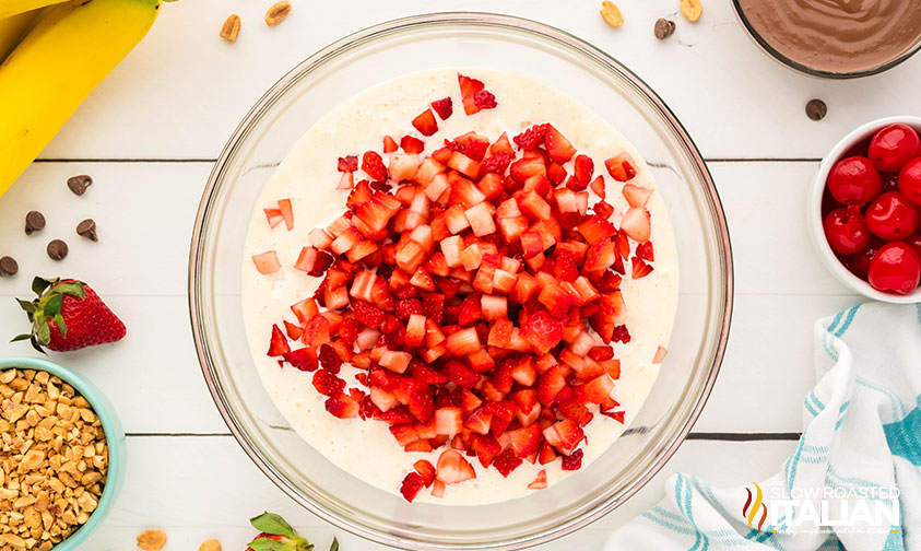 adding diced strawberries to mixture for banana split popsicles